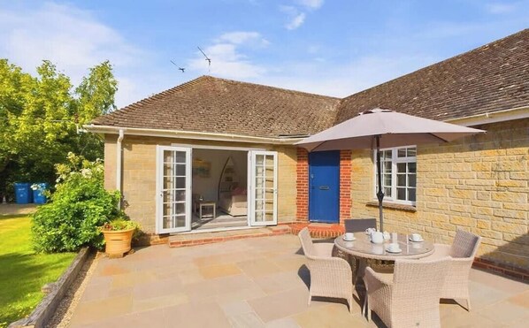 A house with a patio, a blue door, and a table with chairs.