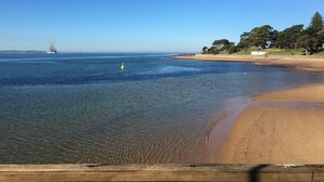 A beach with clear water, a sandy shore, and a distant offshore structure. - Settle Inn, Settlement Rd holiday house, close to shops and beach! (Cowes)
