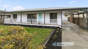 A single-story house with a covered porch, a small front yard with a tree, and a clear sky. - Settle Inn, Settlement Rd holiday house, close to shops and beach! (Cowes)