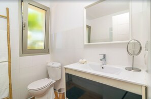 Bathroom features a white toilet, sink, and mirror, with a window and frosted glass design.