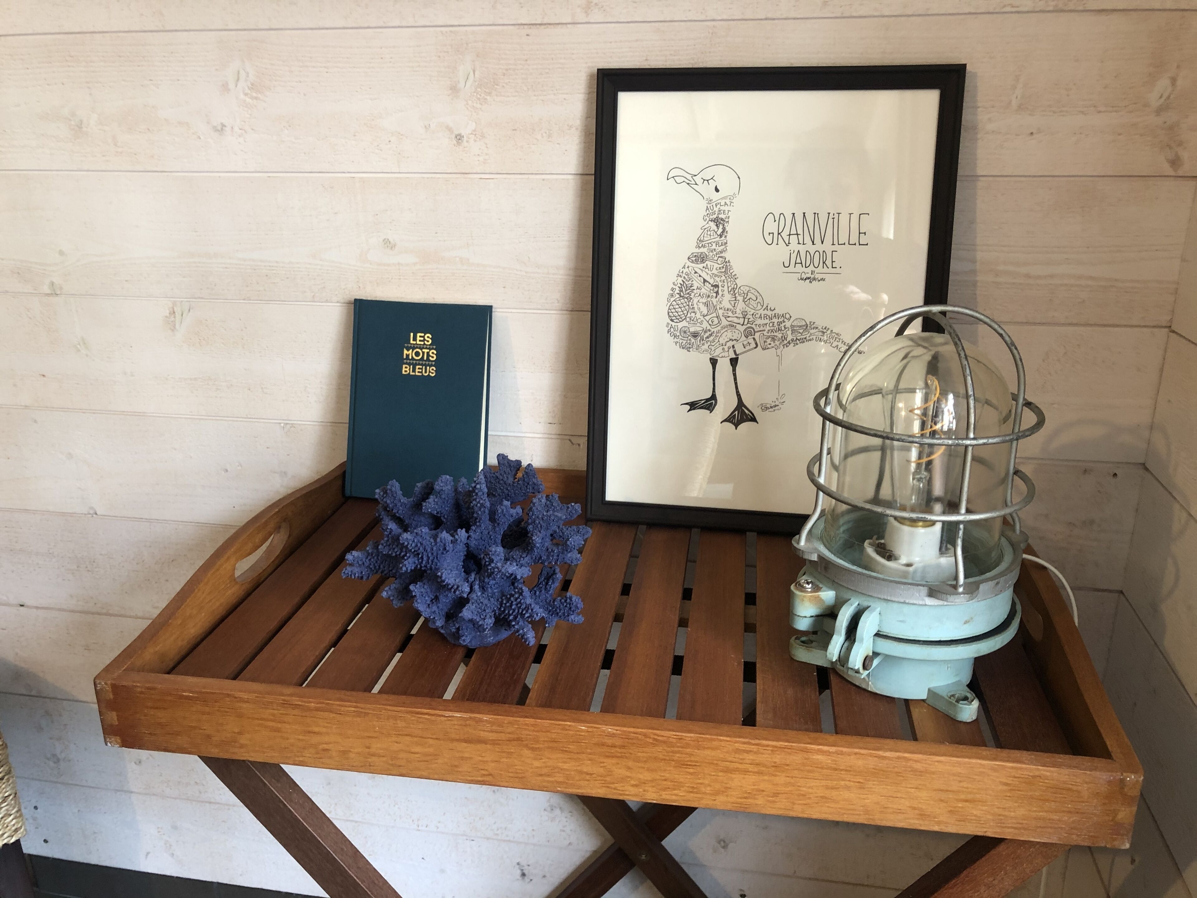 A wooden tray with a framed picture, a book, a blue decorative item, and a vintage-style lamp.
