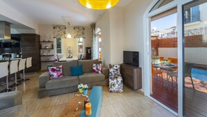 A modern living room with a sofa, a coffee table, a TV, and a dining area with a table and chairs. - Protaras Villa Rocco Near The Beach (Protaras)