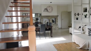 Un vaste salon comprenant un escalier, un coin repas et une cheminée.