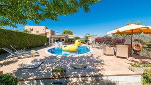 A pool area with lounge chairs, a yellow inflatable float, and an umbrella. - Private Villa with AC, Wifi, huge pool, garden, sun terraces and BBQ, in Selva (Selva)