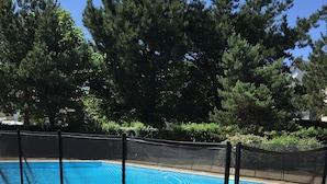 A swimming pool with a safety fence, surrounded by trees and a paved walkway. - PORT CROUESTY apartment with pool (Arzon)