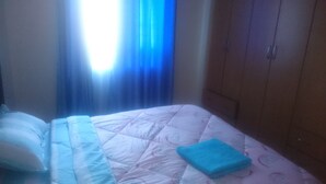 A room with a bed, a blue towel, and a window with blue curtains.