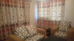 A living room with patterned sofas and curtains with circular designs.