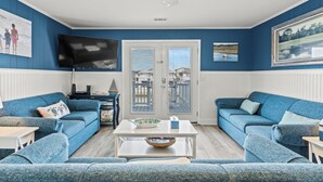 A living room with two blue sofas, a white coffee table, and a TV on the wall. - Ce Chell, Spacious 4 BR Channel Home with Beautiful Channel Views and Floating Dock (NORTH MYRTLE BEACH)