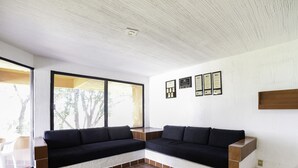 Una sala moderna con un sofá modular, ventanas amplias y premios enmarcados en la pared.