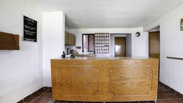 A reception area with a wooden counter, a bulletin board, and a tiled floor.