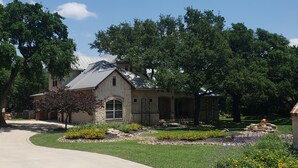 A residential house with a stone facade, a covered patio, and a well-maintained lawn with various plants. - Fair Oaks Ranch Deer Meadow Estates (Fair Oaks Ranch)