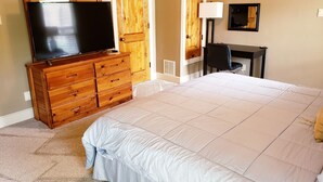 A bedroom with a large bed, wooden dresser, television, desk, and lamp. - Fair Oaks Ranch Deer Meadow Estates (Fair Oaks Ranch)