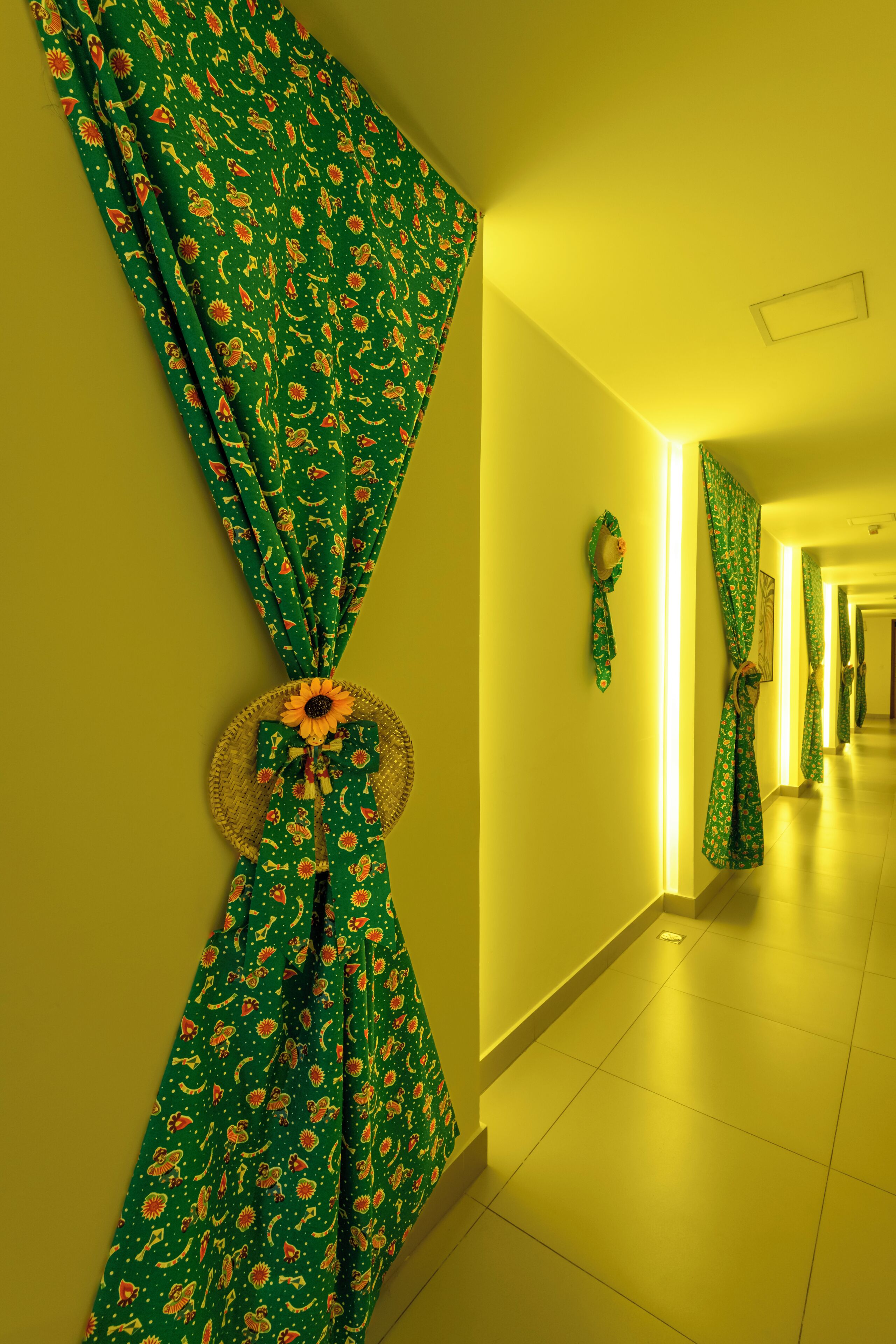 Um corredor com cortinas estampadas em verde e uma cesta trançada decorada com um girassol.