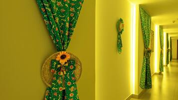 Um corredor com cortinas estampadas em verde e uma cesta trançada decorada com um girassol.