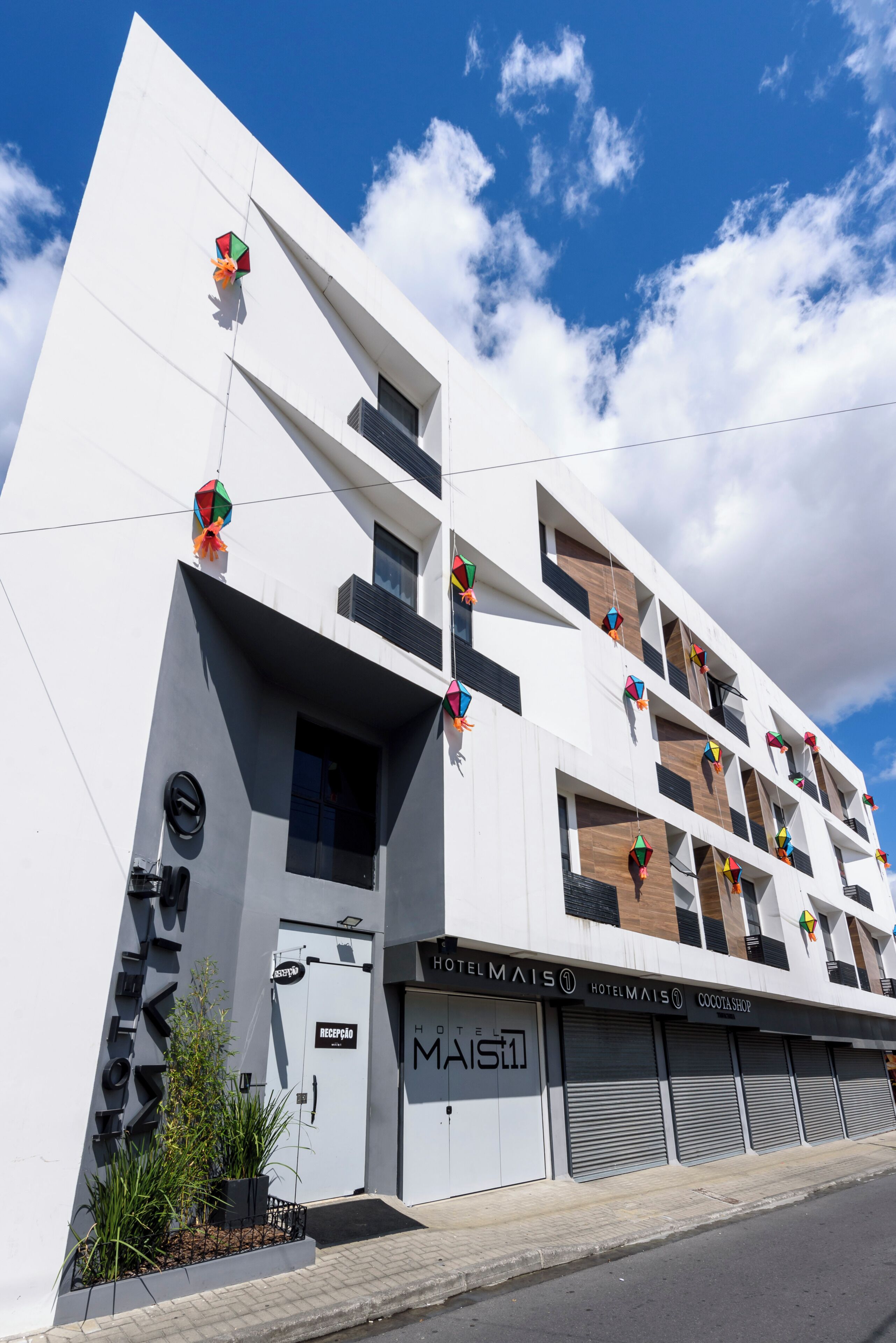 Um hotel moderno com fachada plana, várias varandas e entrada no nível da rua.