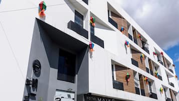 Um hotel moderno com fachada plana, várias varandas e entrada no nível da rua.