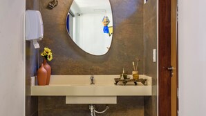 Un baño moderno con un espejo redondo, un lavabo y un inodoro.