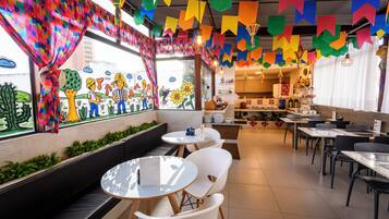 Un restaurant amb decoracions colorades, una barra amb plats i diferents disposicions de seients.