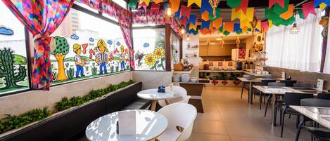 A restaurant with colorful decorations, a counter with food items, and seating arrangements.