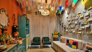 Una sala de estar acogedora con un sofá, dos sillones, un muro decorativo con notas y un techo colorido.