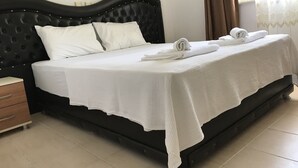 A neatly made bed with white linens and towels, a dark headboard, and a wooden nightstand with a drawer. - Moonlight Apart Hotel (Ortaca)