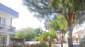 A street view with a building on the left, a tree in the center, and a parked car on the right. - Moonlight Apart Hotel (Ortaca)