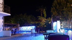 An outdoor patio area with stone flooring, lounge chairs, and tables. - Moonlight Apart Hotel (Ortaca)