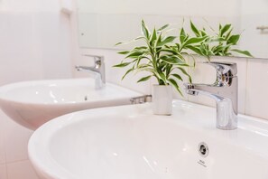 A bathroom with two white sinks, a chrome faucet, and a potted plant. - Pinnawala Backpack Residencies (Rambukkana)
