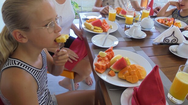 A family dining at a table with various fruits and drinks. - Pinnawala Backpack Residencies (Rambukkana)