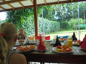 An outdoor dining area with tables, chairs, and a view of greenery. - Pinnawala Backpack Residencies (Rambukkana)