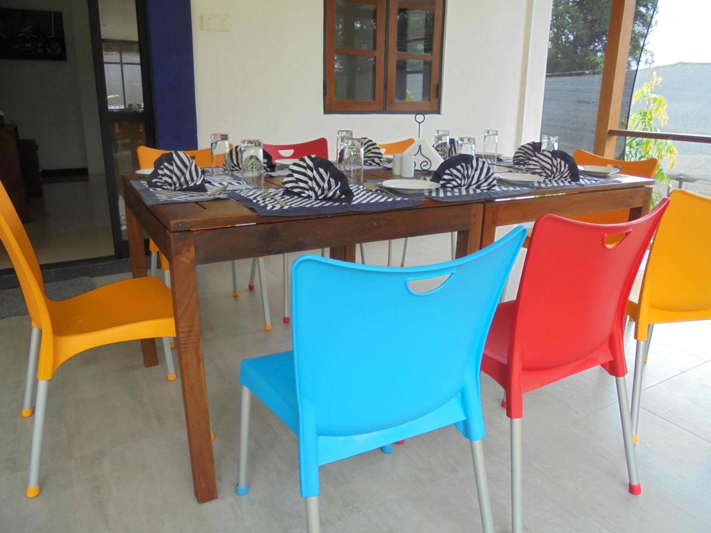 A dining table with zebra-patterned placemats, surrounded by colorful plastic chairs.