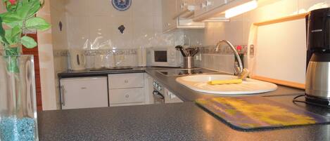 A kitchen with white cabinets, a sink, a coffee maker, and a vase with flowers.