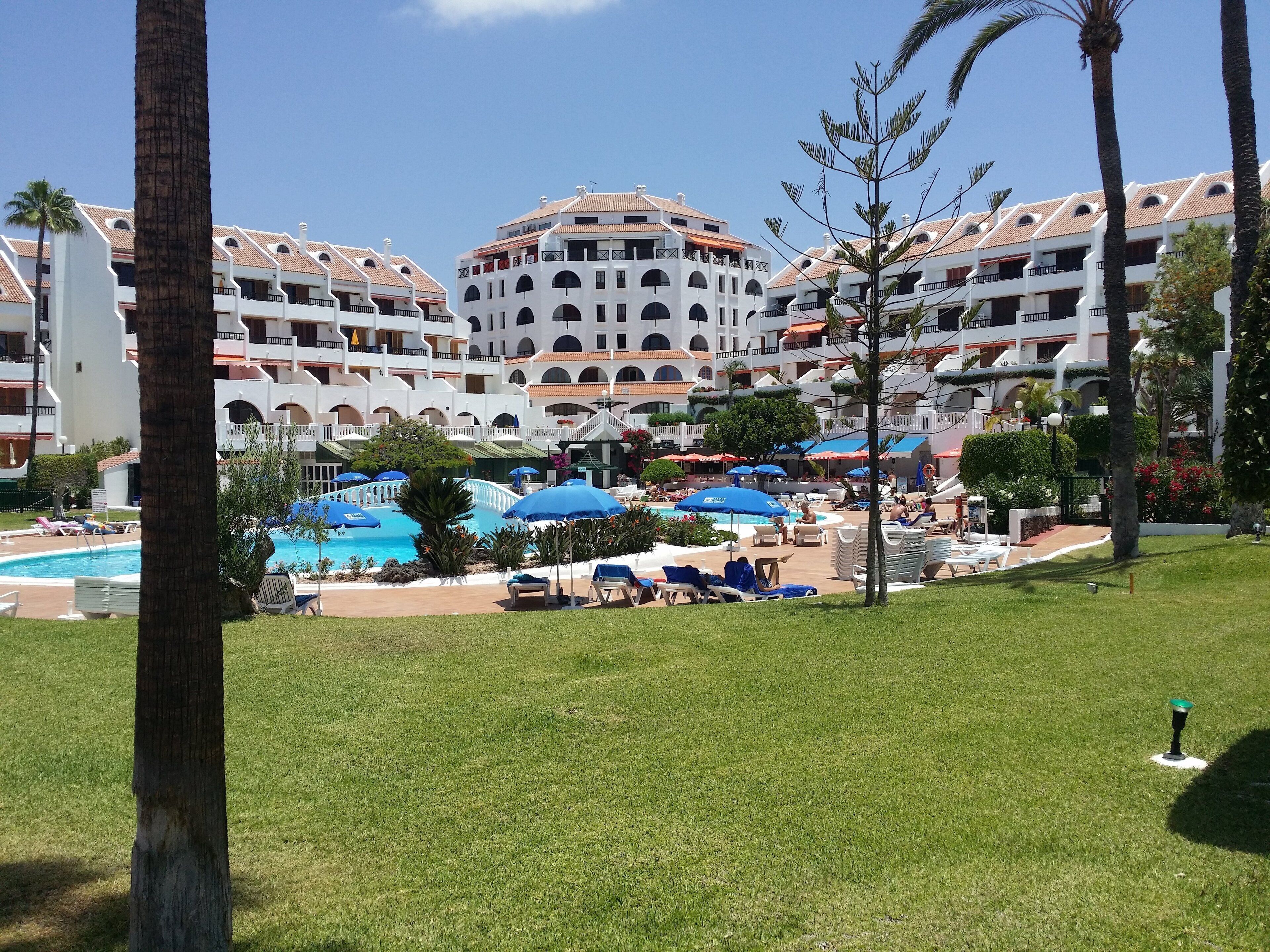 Un complexe hôtelier doté d’une piscine, de plusieurs balcons et d’une pelouse bien entretenue.