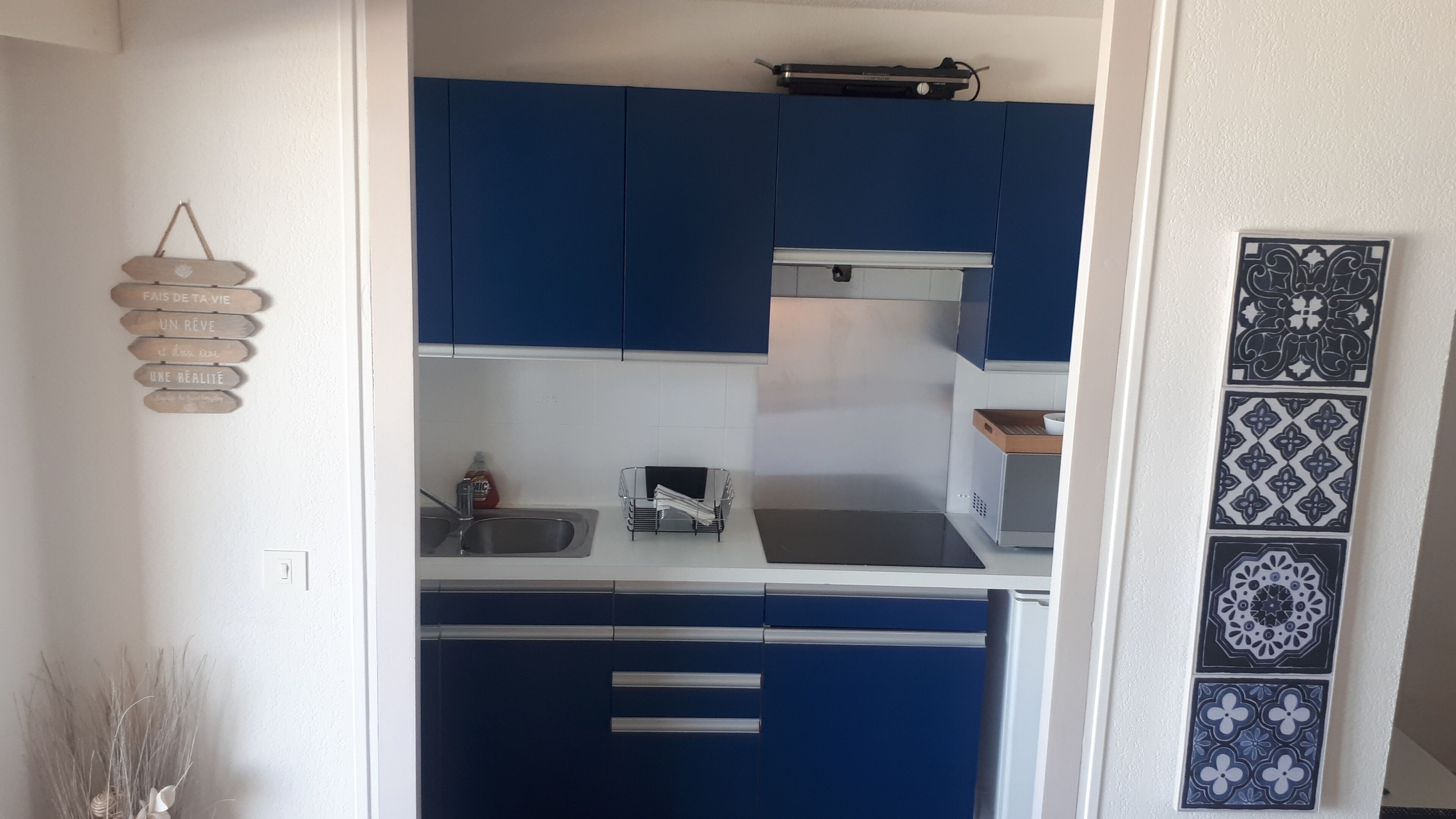 A compact kitchen with blue cabinets, a sink, and a countertop.