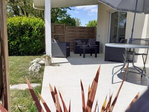 An outdoor patio with a table and chairs, a wooden fence, and a grassy area.