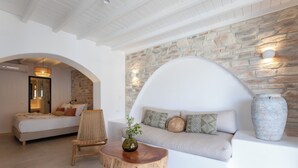 Um interior moderno com parede de pedra, um sofá, uma mesa de madeira com um vaso e uma cama com almofadas.