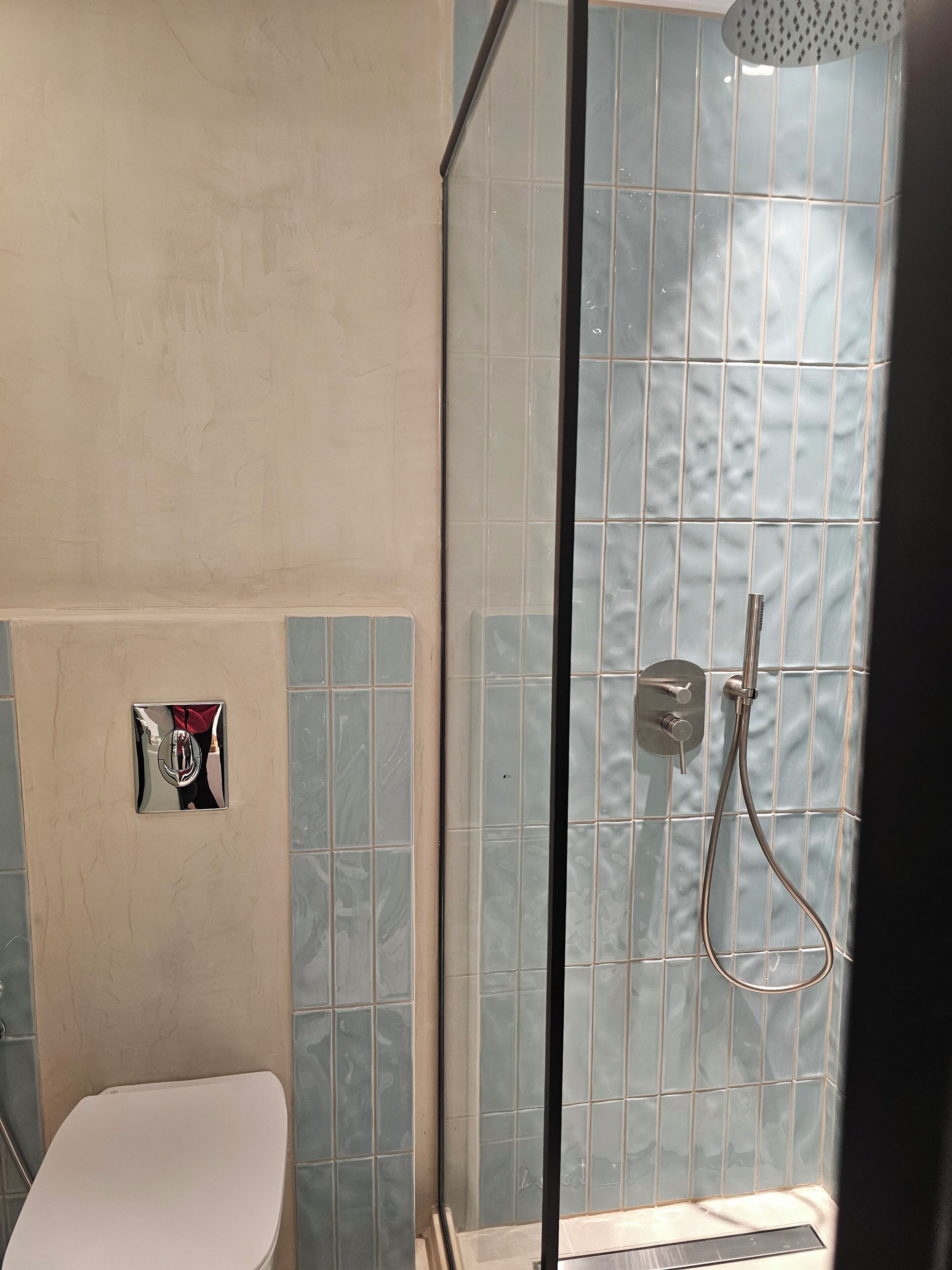 A bathroom with a shower, toilet, and a towel rack.