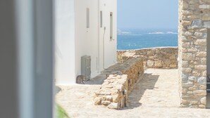 Uma estreita trilha de pedra que leva a edifícios brancos, com vista para o mar.