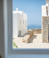 Un estrecho sendero de piedra que conduce a edificios blancos con vista al mar.