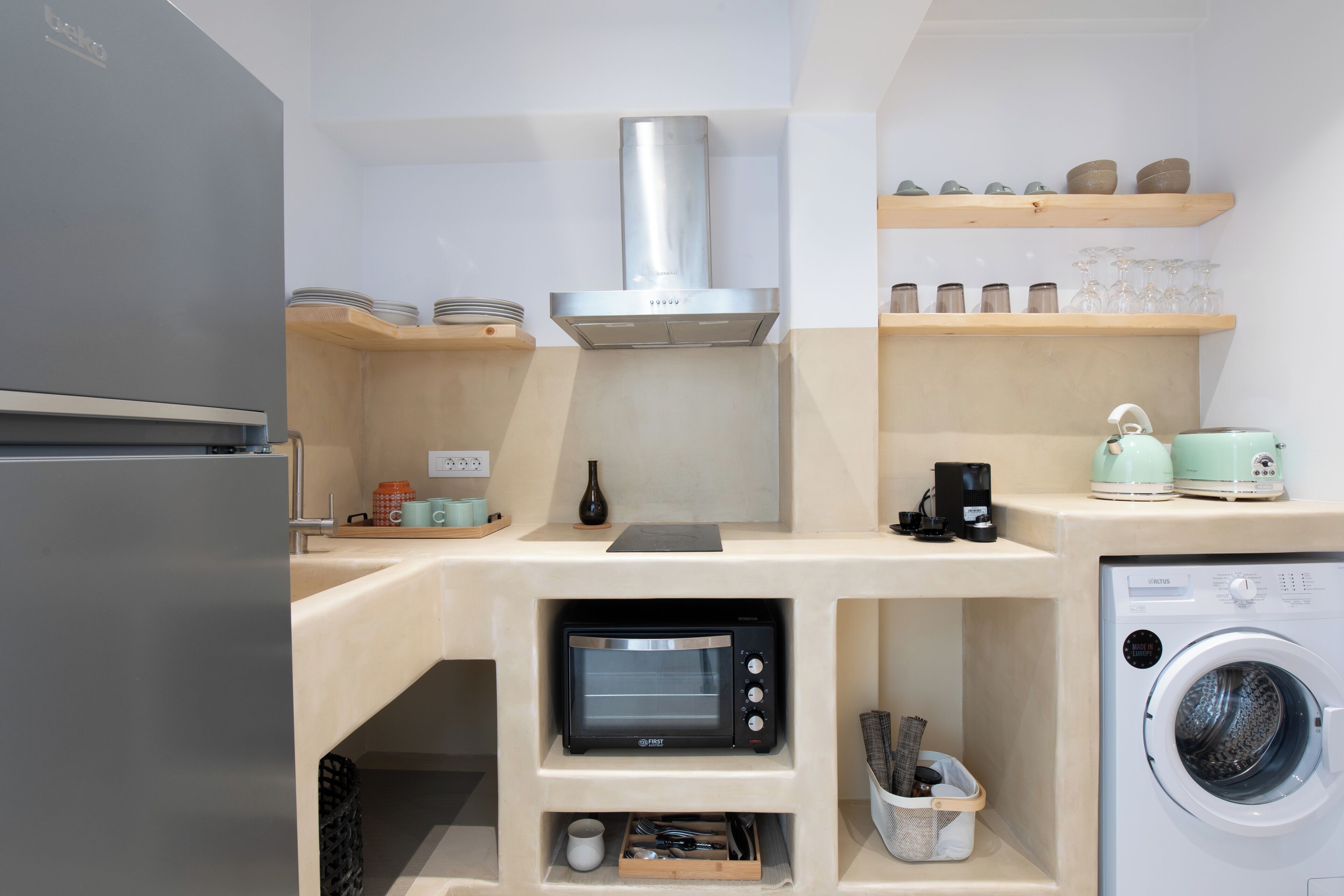 A compact kitchen with a built-in oven, microwave, and a washing machine.