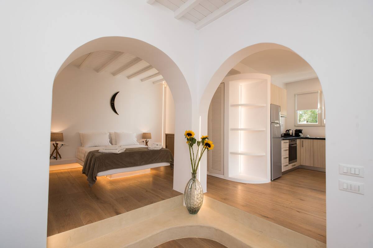 Une chambre à coucher moderne avec un lit, un vase de fleurs et une vue sur la cuisine.
