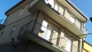 A multi-story building with balconies, windows, and a street lamp. - Casa Valentina (Linguaglossa)
