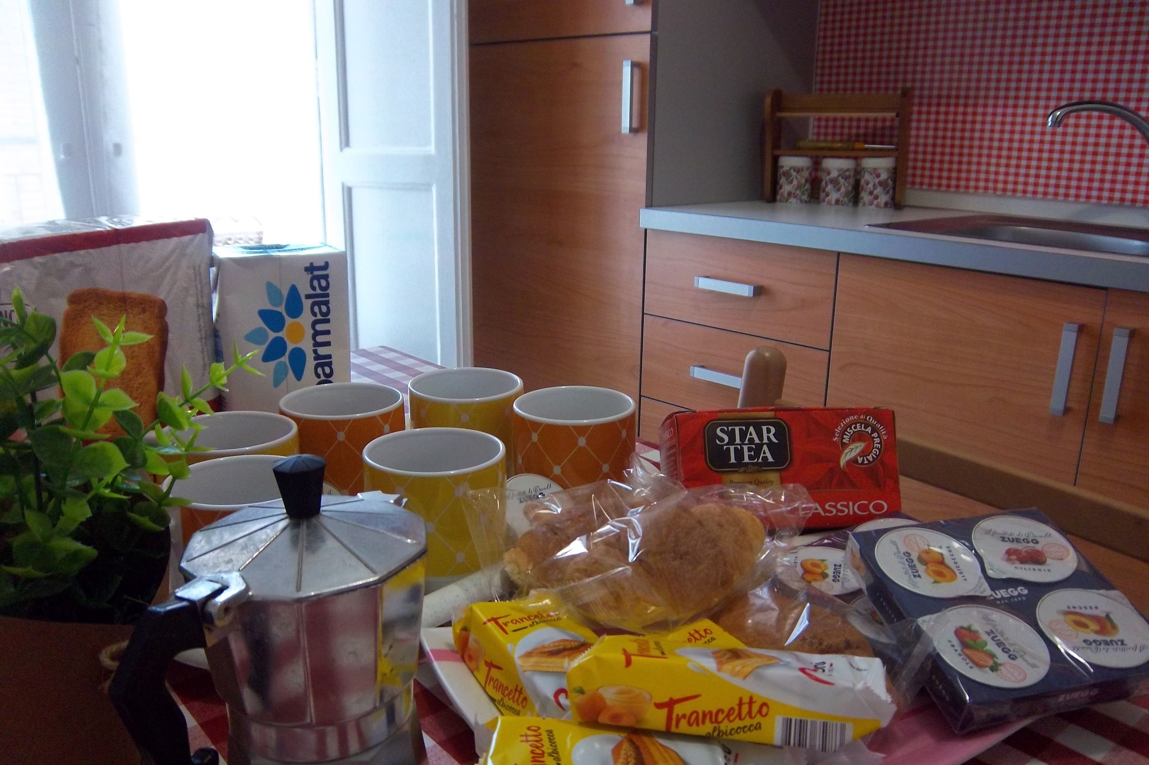 A kitchen with a coffee maker, cups, and food items on the counter.