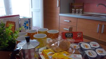 Una cocina con una cafetera, tazas y alimentos en la encimera.