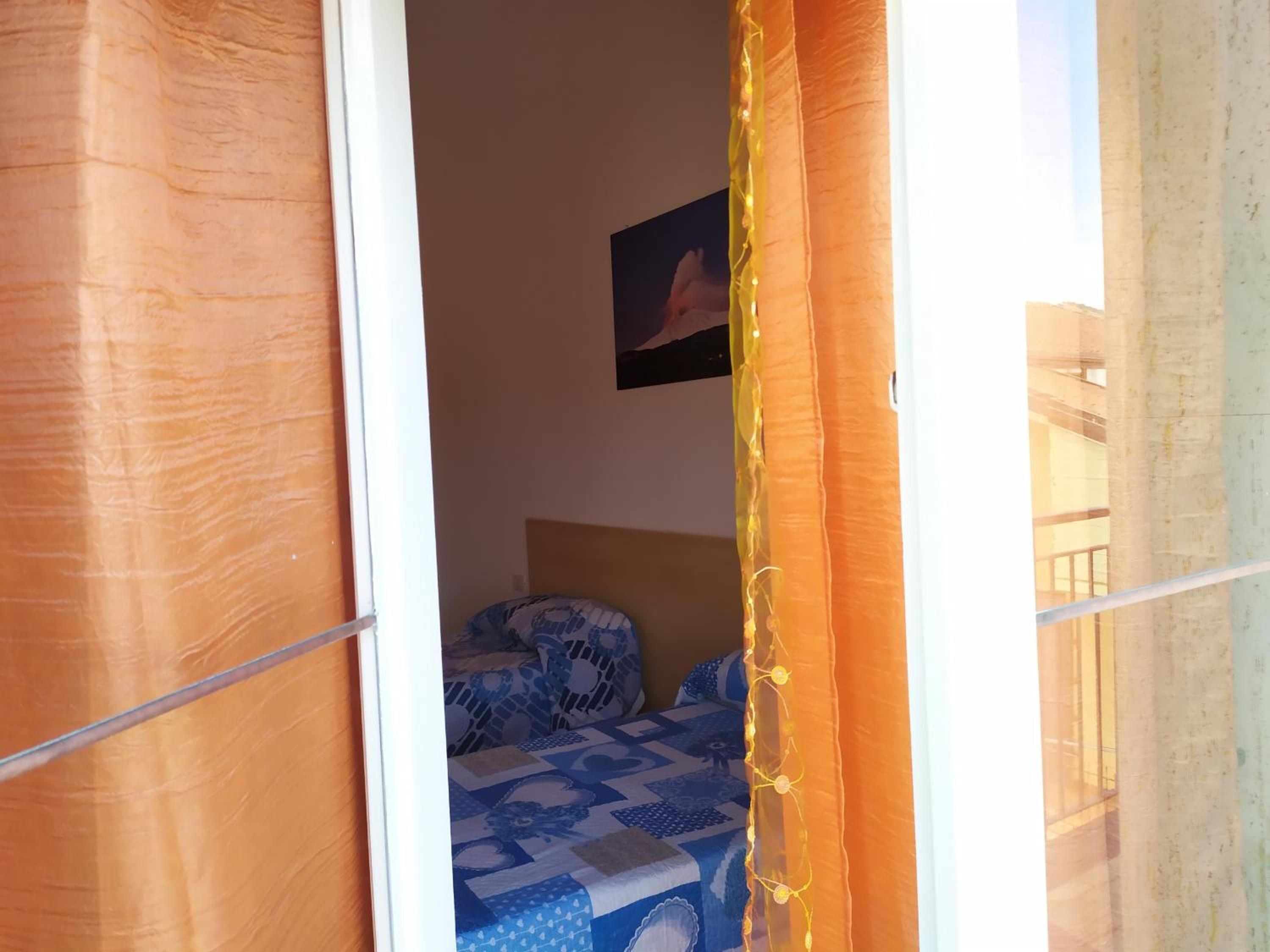 Een slaapkamer met een bed met beddengoed met een patroon, een schilderij aan de muur en een raam met gordijnen.