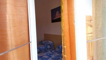 Een slaapkamer met een bed met beddengoed met een patroon, een schilderij aan de muur en een raam met gordijnen.