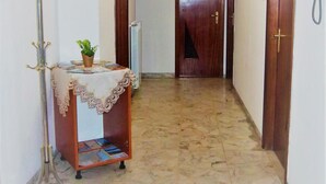 A hallway with a wooden door at the end, a radiator, and a telephone on the wall. - Casa Valentina (Linguaglossa)