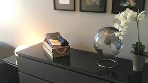 A modern room with a dark wooden dresser, a globe, a potted orchid, and framed pictures on the wall. - Private room in a shared, centrally located apartment (St. Hanshaugen)