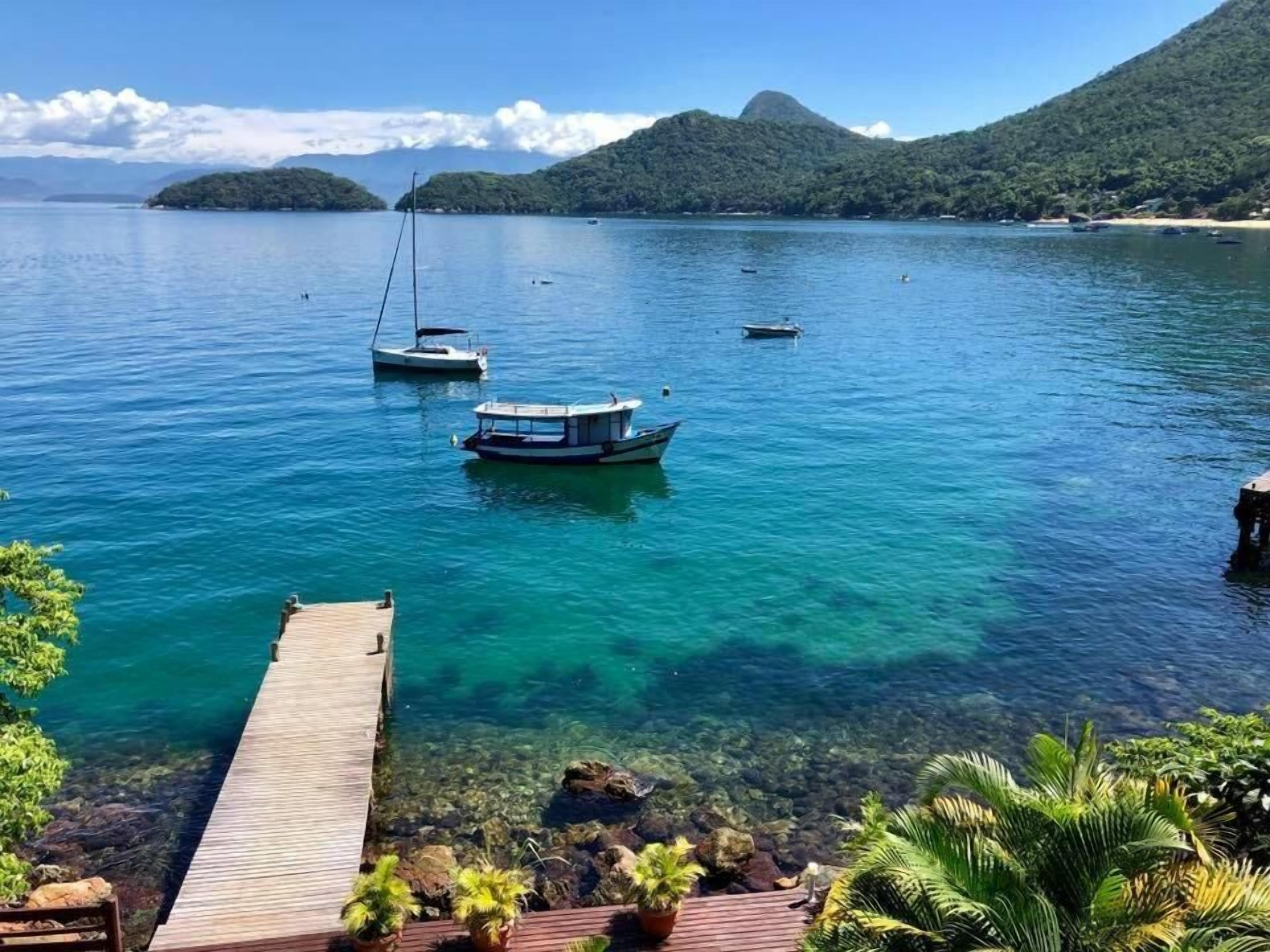 Une vue dégagée sur un lac paisible, avec des bateaux, une jetée en bois et une végétation luxuriante.