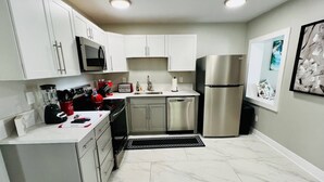A modern kitchen with white cabinets, stainless steel appliances, and a marble floor. - #7 Heated Pool, Private Patio & Grill (Fort Lauderdale)